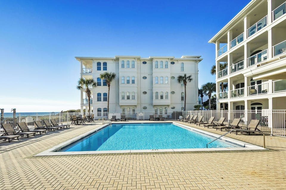 Beautiful community pool complete with sun loungers overlooks the emerald waters of the Gulf.