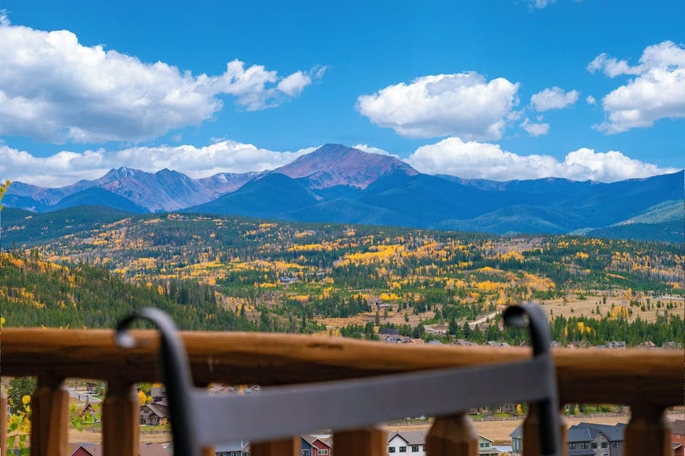 Spectacular mountain panorama showcases dramatic peaks and golden autumn foliage across the valley landscape.