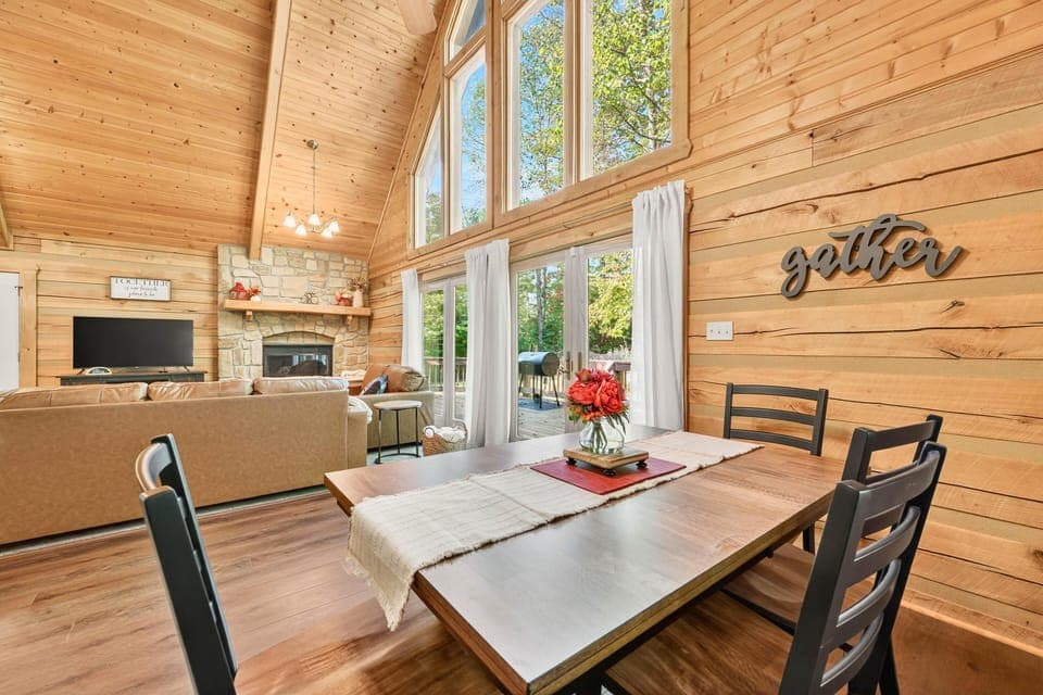 Sunlit dining area with vaulted ceilings and forest views