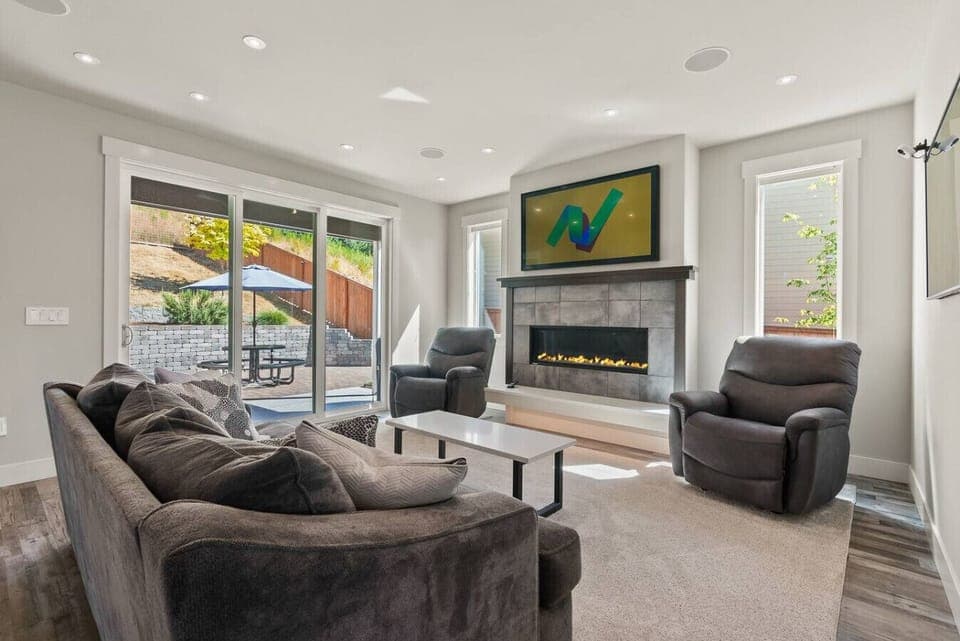 Cozy up in the modern living room with plush seating, a sleek gas fireplace, and sliding doors that open to the sunny patio for effortless indoor-outdoor relaxation.