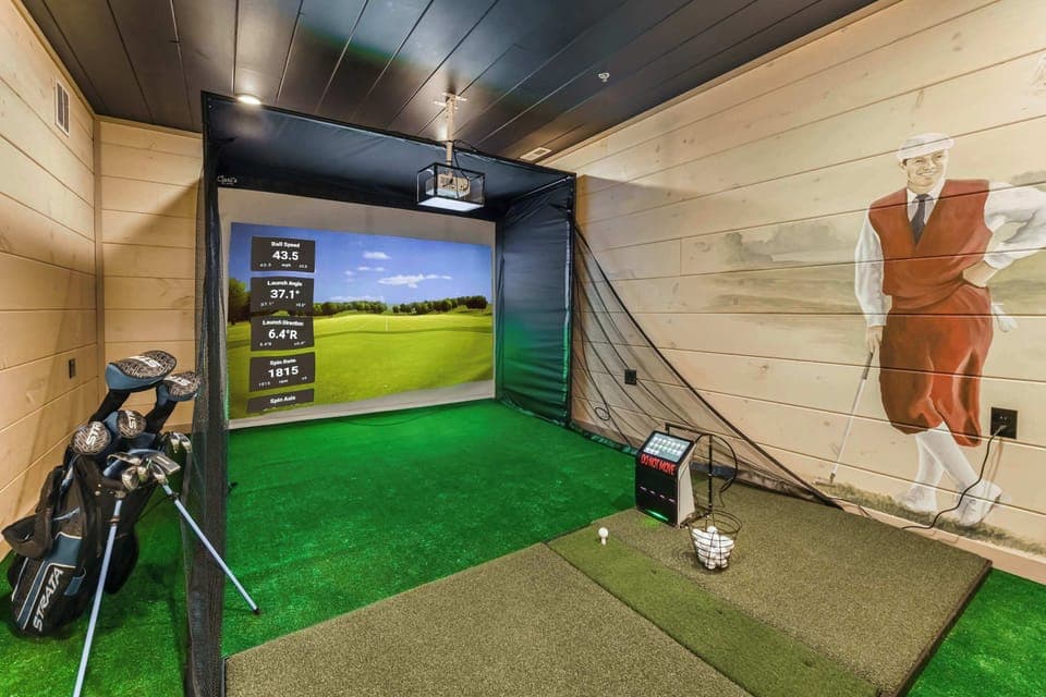Indoor golf simulator room with digital tracking and vintage golf mural