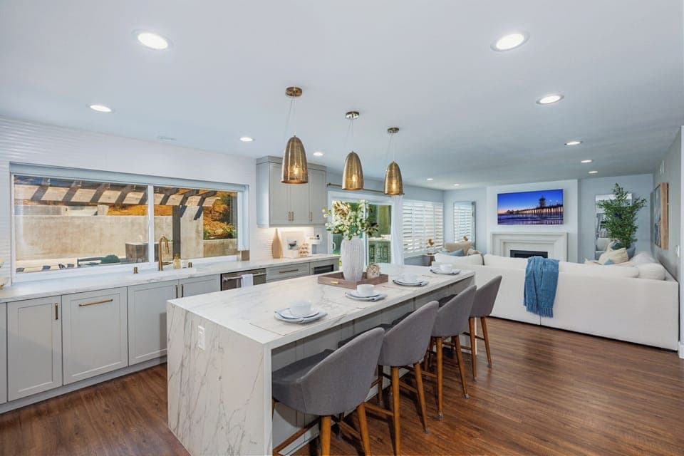 Open-concept kitchen with barstool seating, waterfall counter island, and pendant lights.