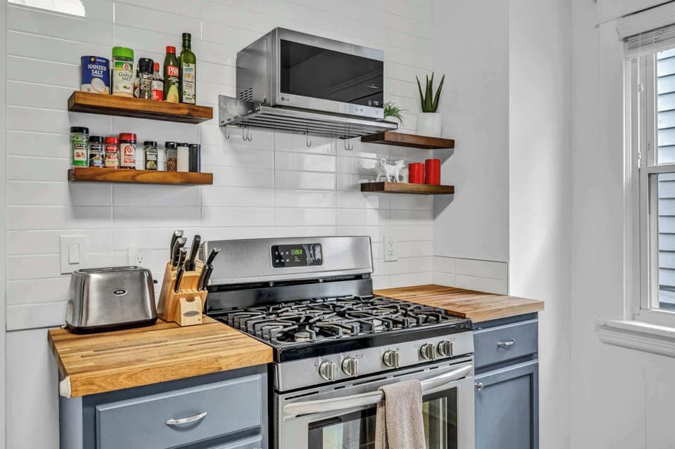 Charming home kitchen with stainless appliances, wood accents, and open shelves — perfect for morning coffee or cooking together.
