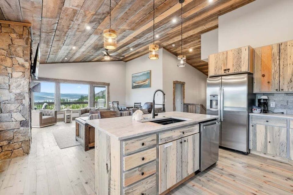 Cook with mountain views in this rustic-elegant kitchen at 128 GCR 4034 featuring reclaimed wood, stone fireplace, and modern appliances.