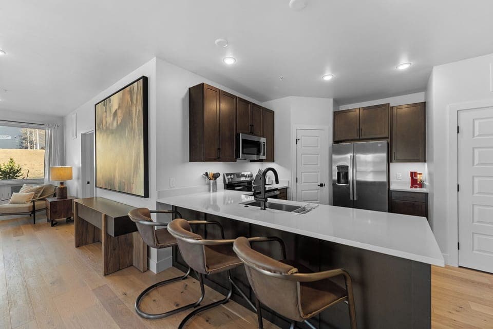 Full kitchen with stainless steel appliances, and breakfast bar seating three.