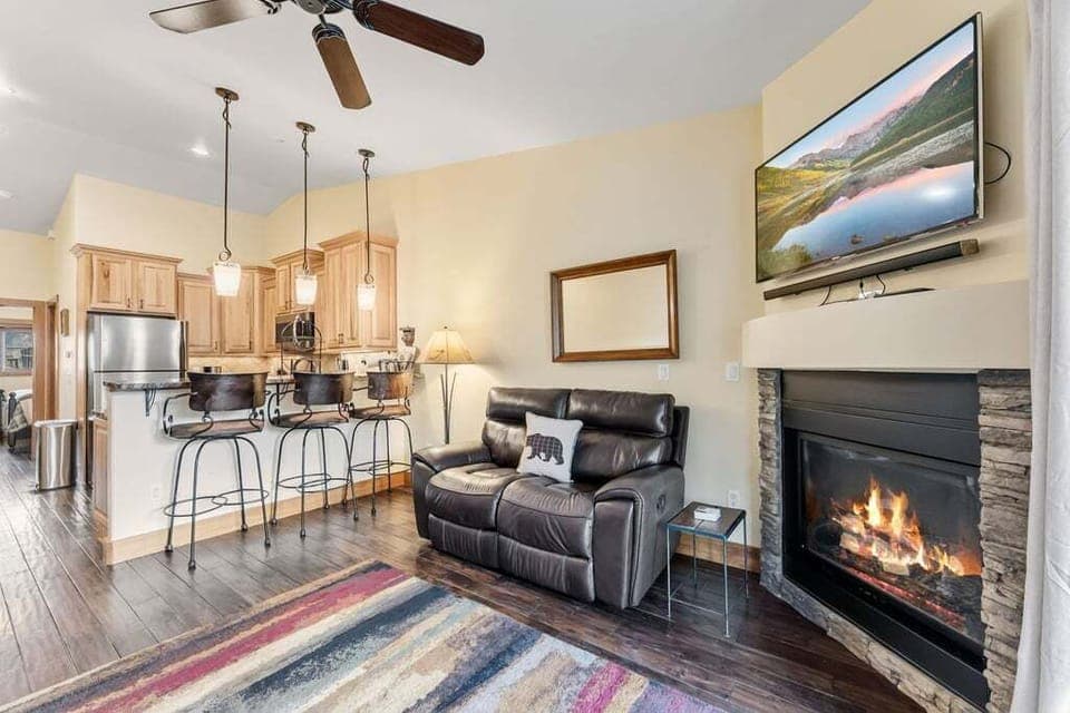 Unwind in this cozy living space with crackling fireplace warmth and mountain views on the large TV.