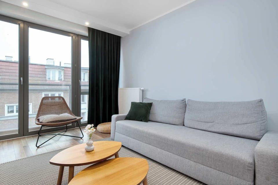 Living room with city view – Bright interior featuring a modern gray sofa and wooden accents.
