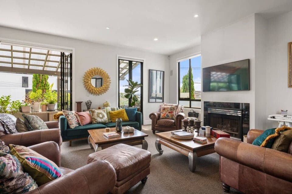 Open plan kitchen, dining and living, complete with cosy couches, and views over the harbour and sky tower