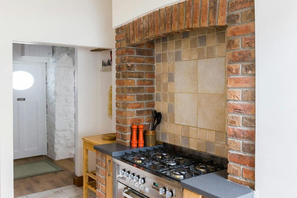 Electric oven and gas hob range set within old brick chimney breast