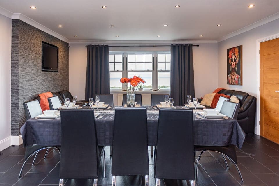 Dining table seating eight with extra chairs and a breakfast bar for four, comfortably catering for twelve or more. Fully stocked with cutlery, dining essentials, and table linens.