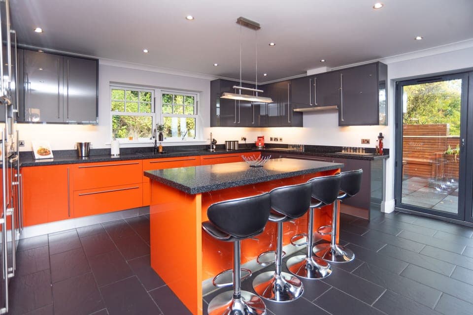 Bright breakfast bar seating four, ideal for hosting larger groups, set within a sleek modern kitchen with fully integrated appliances.