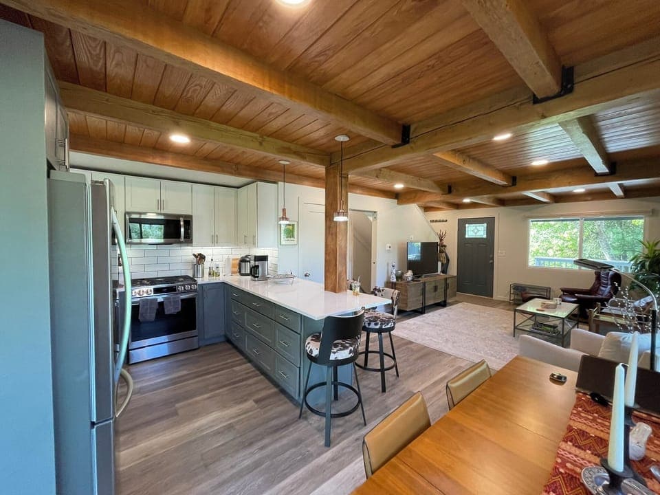 Renovated kitchen with quartz island, seating, and open connection to LR