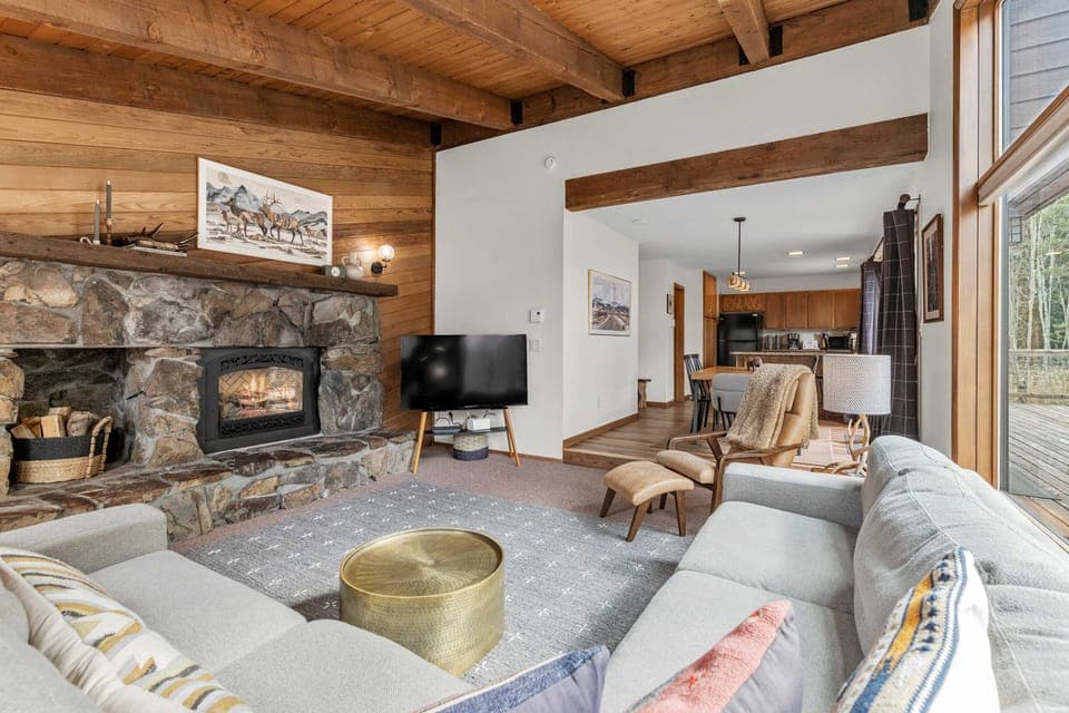 Relax by the fireplace in a cozy, sun-drenched living room with forest views!