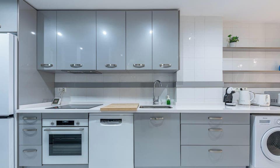 Modern kitchen featuring sleek gray cabinets, white countertops, and essential appliances.