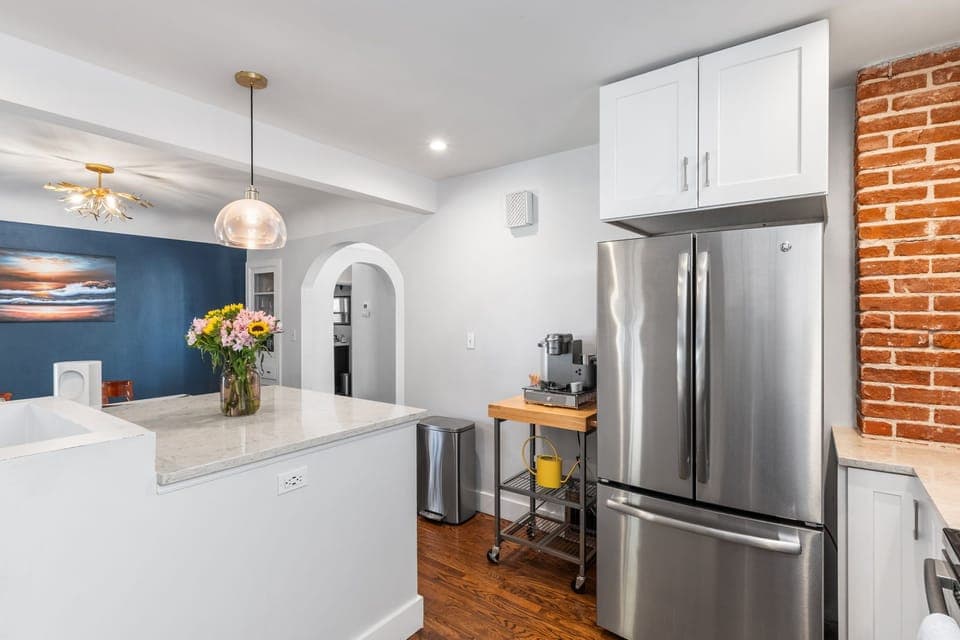 Your chef-inspired kitchen awaits with gleaming stainless steel appliances and spacious counters perfect for morning coffee or evening wine. The exposed brick wall adds warmth while modern fixtures create an inviting space to cook and connect.