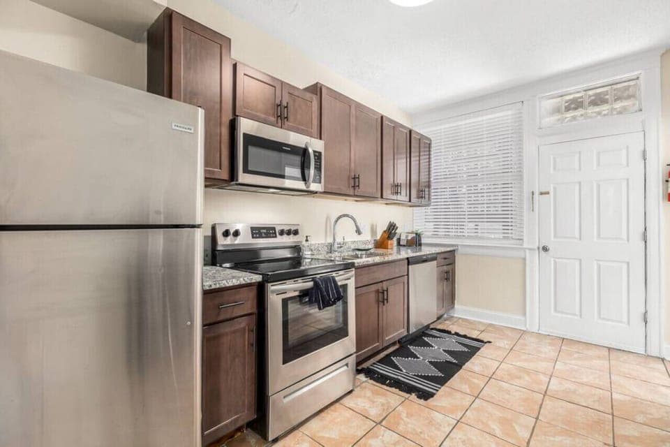 Full size kitchen with stainless steel appliances including microwave, dishwasher, sink with garbage disposal, stove and oven, and fridge.