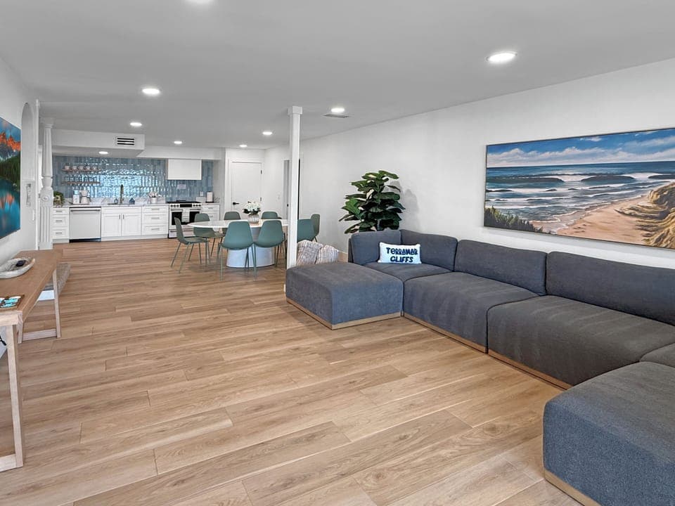 Your open-plan living space flows seamlessly from the plush sectional sofa to the modern kitchen, perfect for relaxing after beach days.