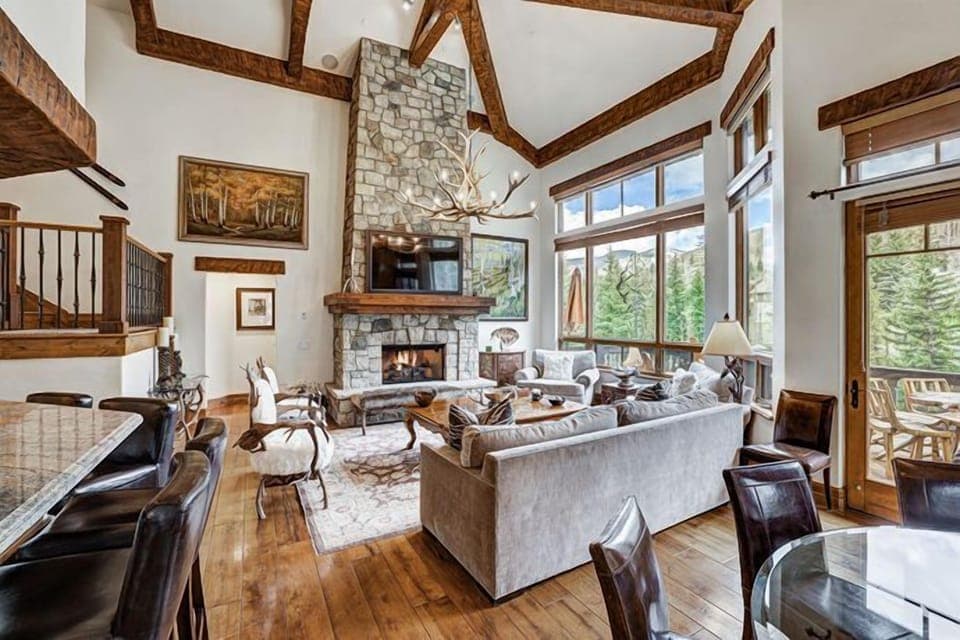 Spacious great room with vaulted ceilings, fireplace, and large windows framing the alpine scenery.