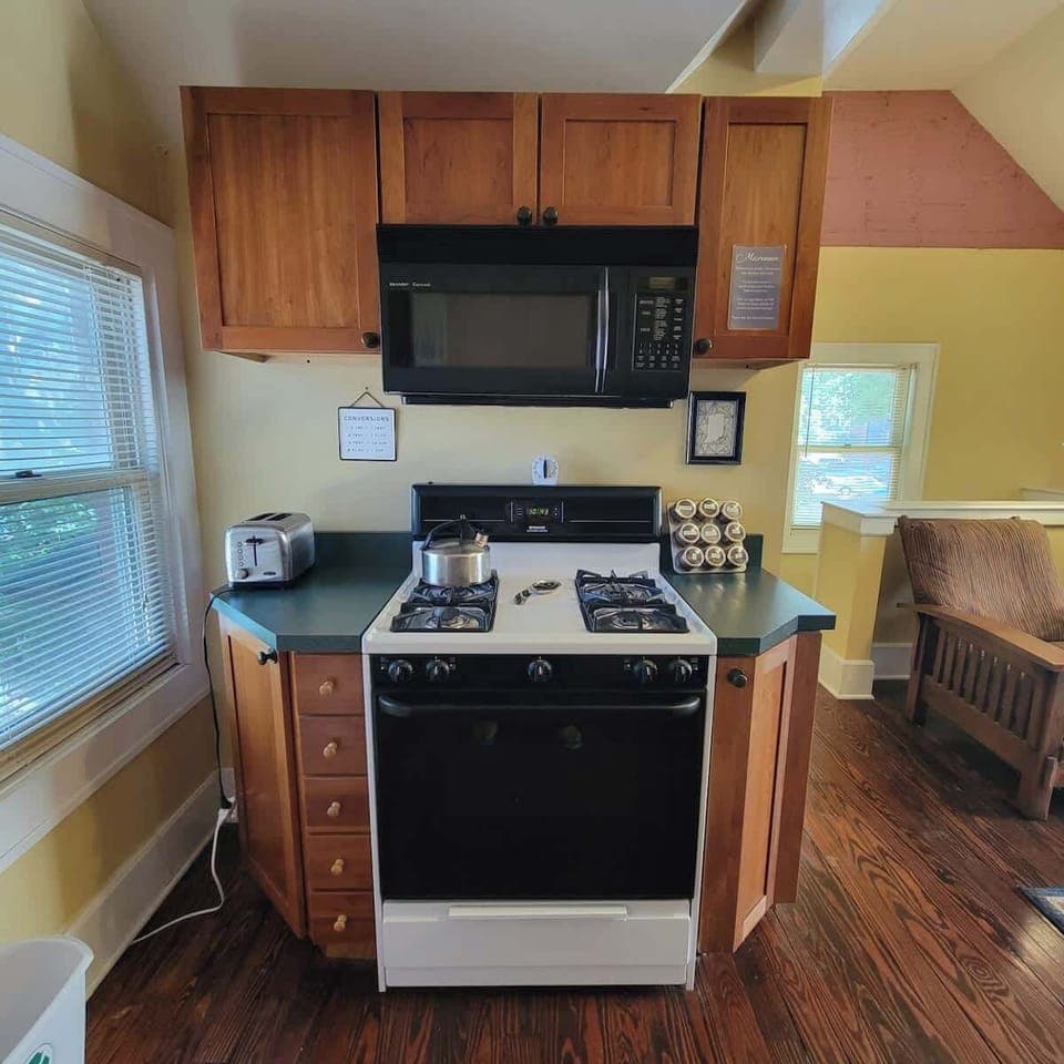 Kitchen has a microwave, toaster, tea kettle, spices and cooking oil as well as cookie sheets and pots and pans. 