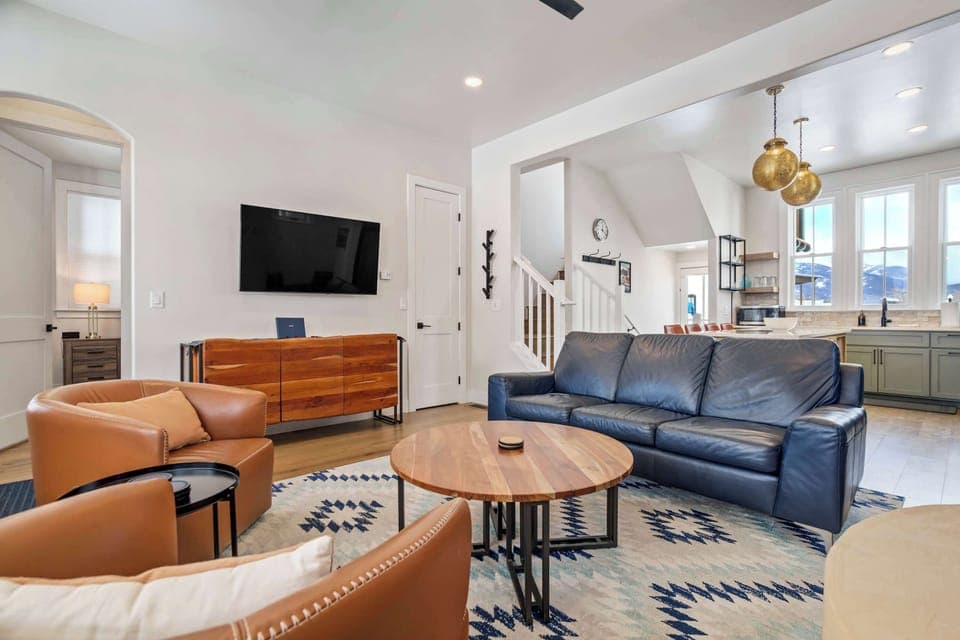This wide view shows the open living room with plush seating, a Smart TV, and easy flow into the dining nook and kitchen. Soft colors and layered textures create a comfortable, inviting gathering space.