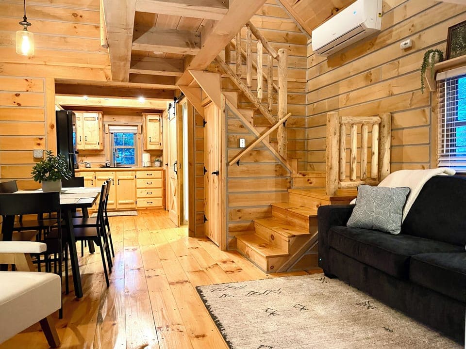✨ Imagine relaxing in this cozy log cabin living space—gather for meals, play games, or unwind after a day in Shipshewana. Your home away from home awaits! 🥰🪑