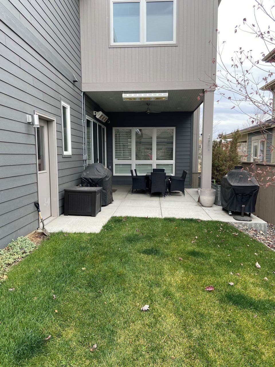 Private backyard with grass and covered patio, grill