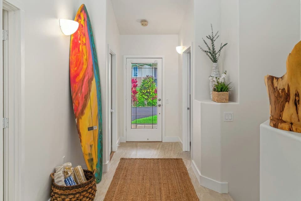 Entry hallway with surf art and tropical views sets a relaxed island tone.