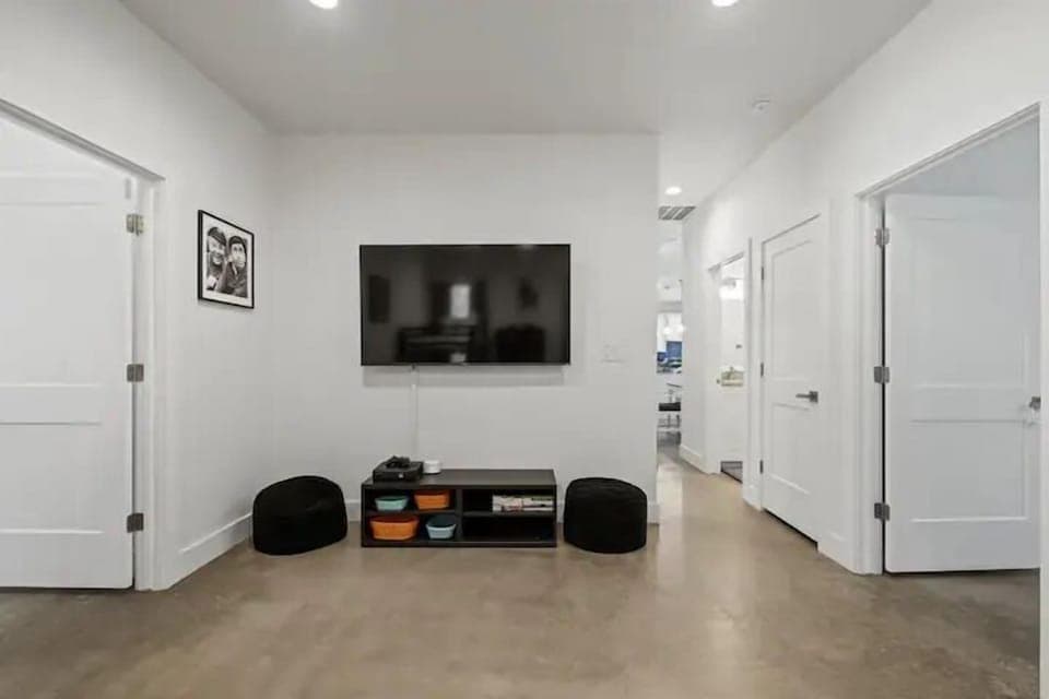 A clean, modern living space with a wall-mounted TV, cozy seating, and simple, organized décor.