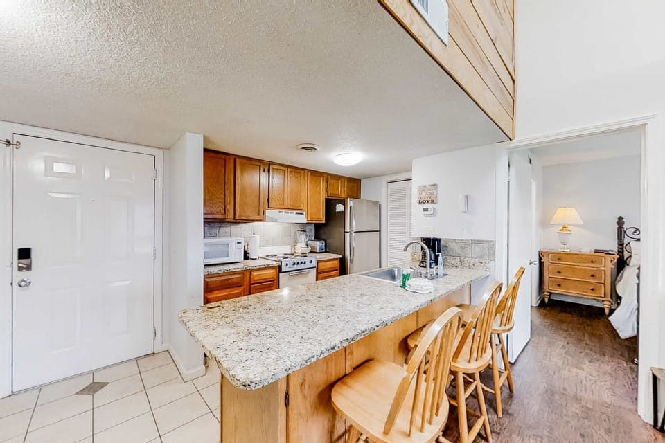 Fully equipped kitchen with granite countertops, bar seating, full-size appliances, and open layout. Ideal for family meals and group gatherings.