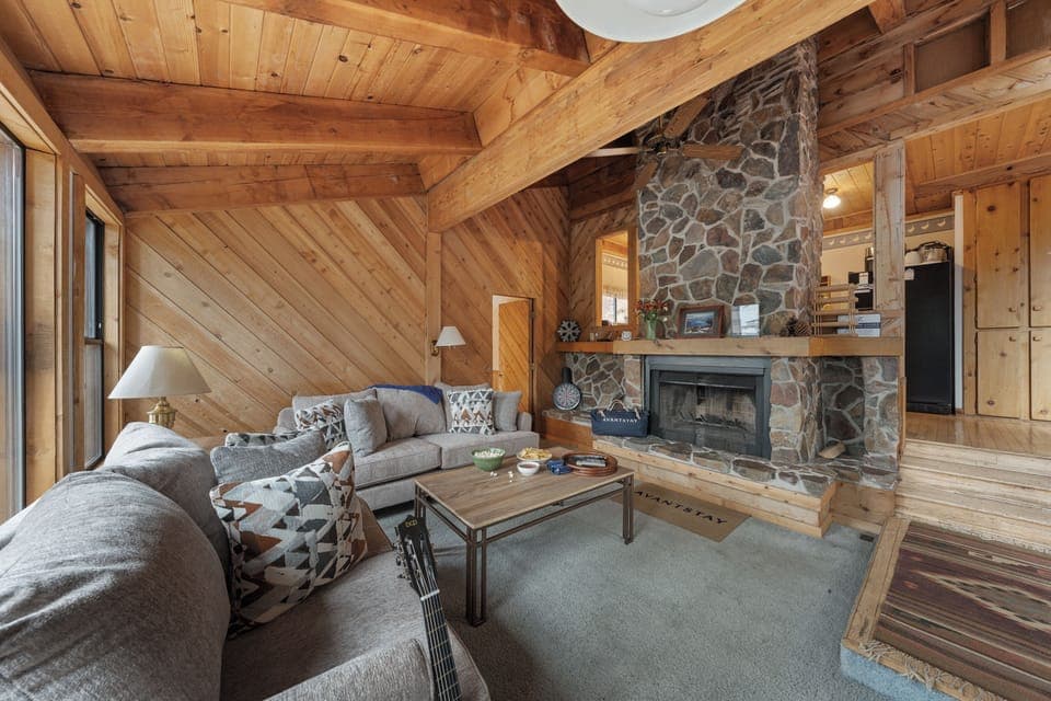 Cozy mountain-chic living room with a stone fireplace and warm timber interiors—your perfect Tahoe retreat.