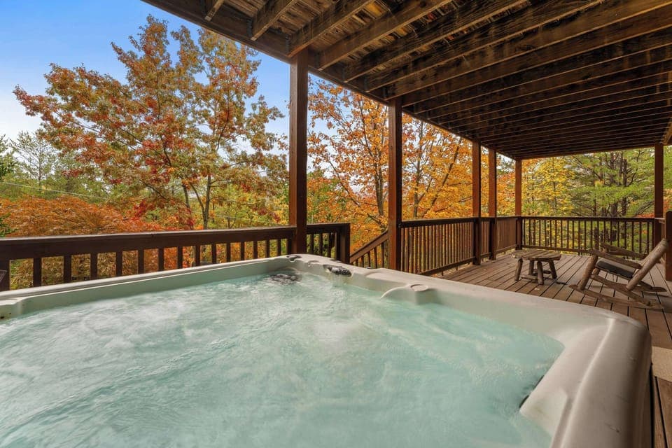 Covered private hot tub on the lower deck with forest scenery.