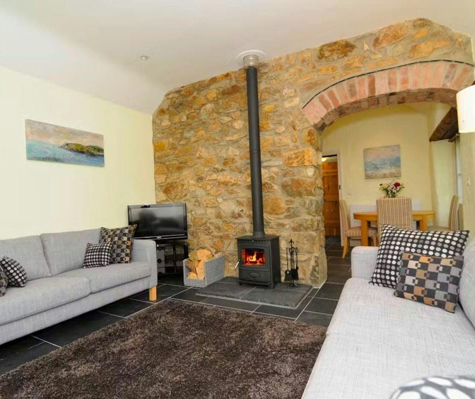 Wood burner, two sofas with cushions and TV on unit