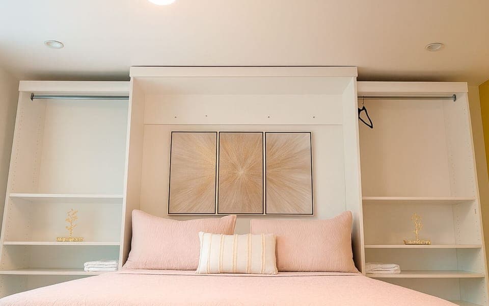 Cozy sleeping area in The Gold Room, with textured bedding, gold artwork, and open shelving for a clean, modern feel.