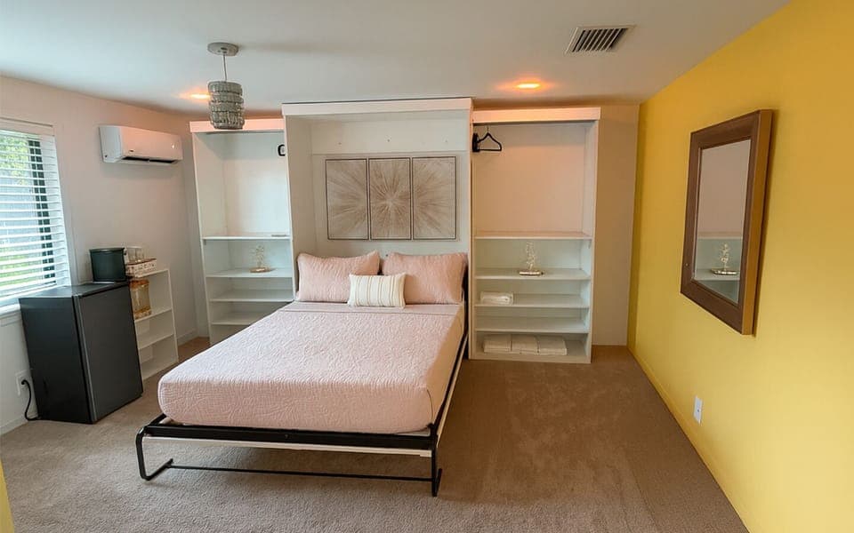 The Gold Room at Garden of Manors, featuring a spacious bed framed by built-in closets, soft lighting, and warm gold accents in Wilton Manors.