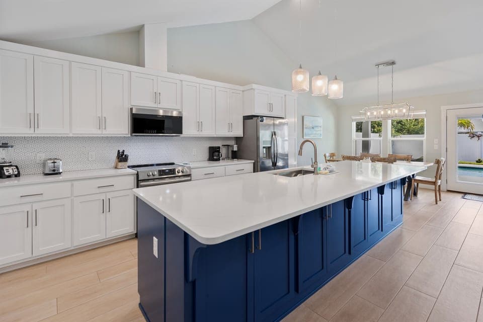 Your gourmet kitchen features a stunning blue island, gleaming countertops, and top-tier appliances—perfect for creating memorable meals together.