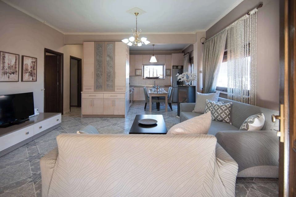 Spacious open-plan living and dining area with soft lighting and cozy furnishings, ideal for gathering with family or friends after a day of exploring Olympiada.