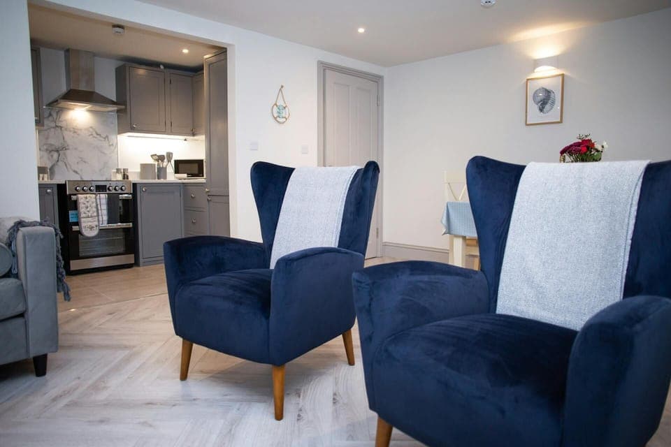 Two large armchairs in the living area with a view into the kitchen