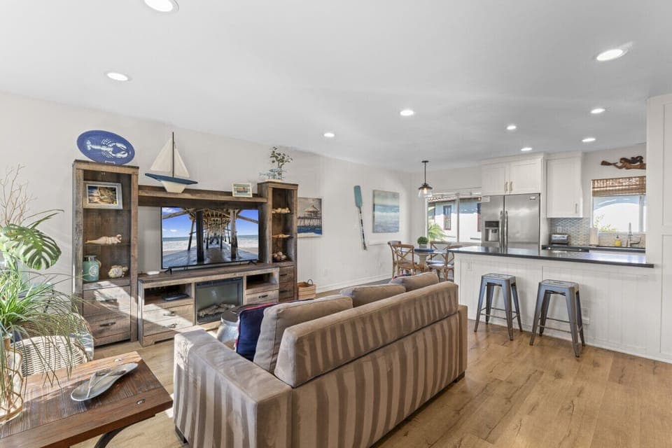 Bright coastal living space with comfortable seating, a 55` Smart TV, and an open kitchen—perfect for relaxing after beach days.