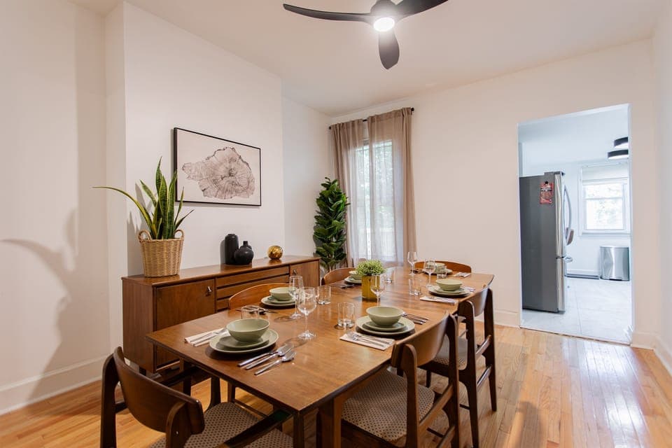 Warm, inviting dining space with a mid-century 6-seater table, natural wood tones, and lush greenery, perfect for shared meals and gatherings.