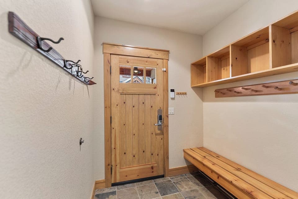 Entryway with a bench, storage shelves, and hooks.