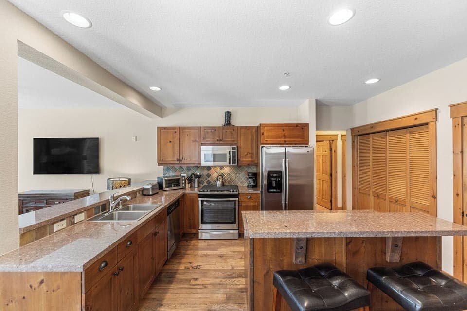 Full kitchen with stainless steel appliances and breakfast bar.