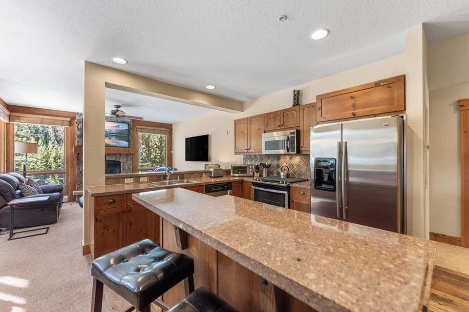 Full kitchen with stainless steel appliances and breakfast bar.