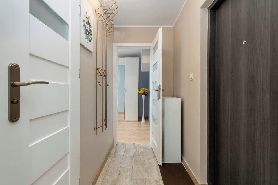 An entry hallway with a wardrobe, a bathroom door, and bright wooden flooring.