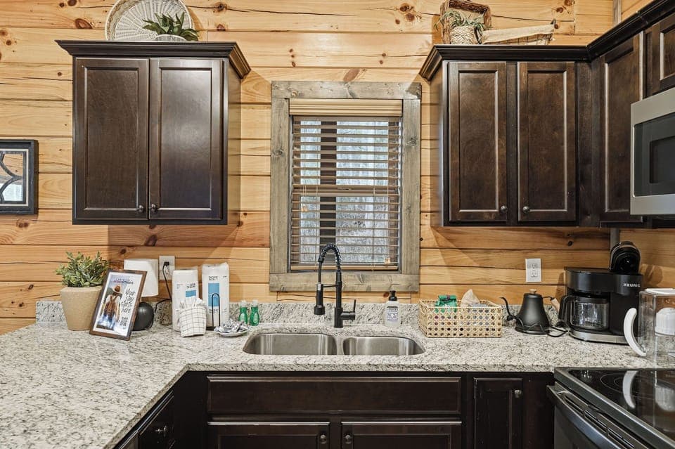 Your fully equipped kitchen features granite counters, dark wood cabinets, and modern appliances for preparing memorable meals together.
