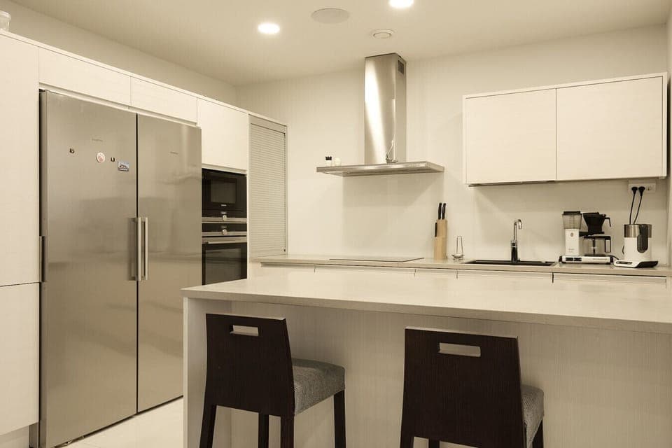 Fully equipped high-end kitchen featuring minimalist white cabinetry and a professional-grade atmosphere.