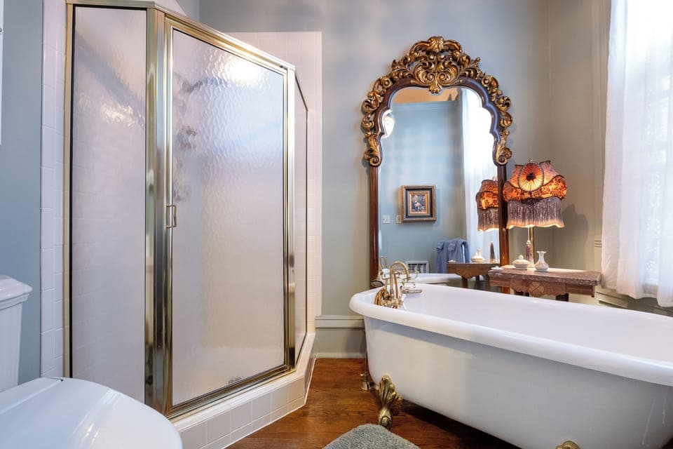 Private bathroom with clawfoot bubble bathtub, glass-enclosed shower, Japanese-style bidet toilet, and elegant vintage-style fixtures