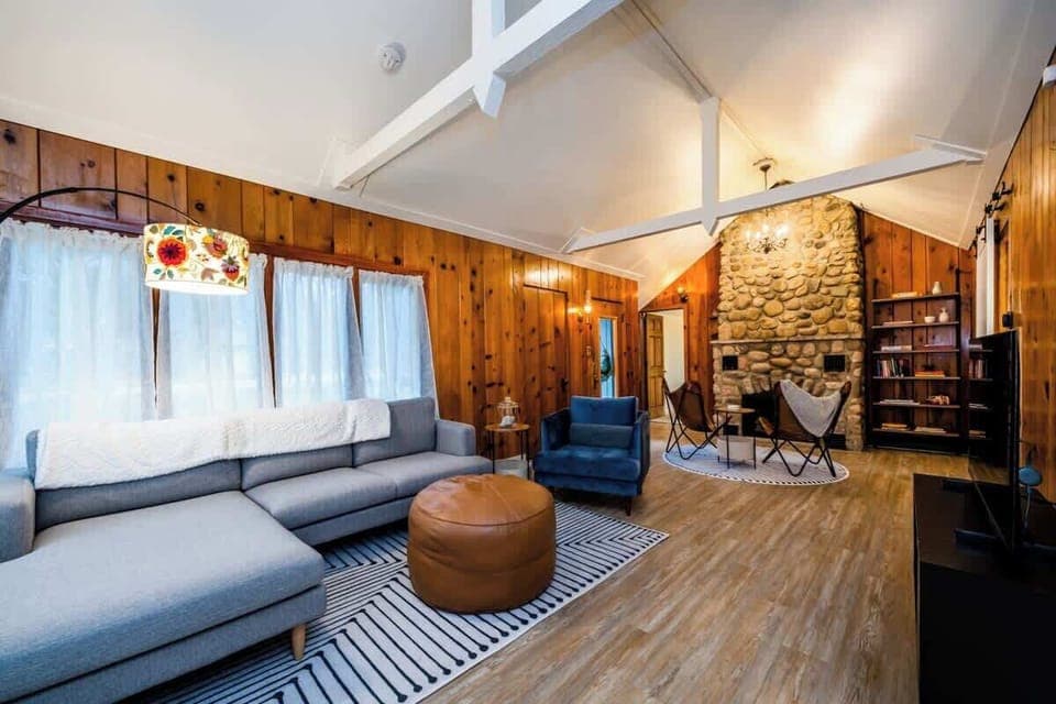Cozy living room with vaulted ceilings, rustic wood paneling, and a beautiful stone gas burning fireplace. 