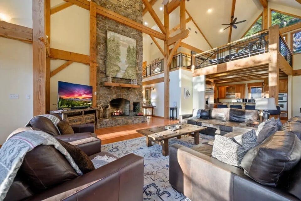 Living Room: Inviting space with high ceilings, stone fireplace, and panoramic views of nature!