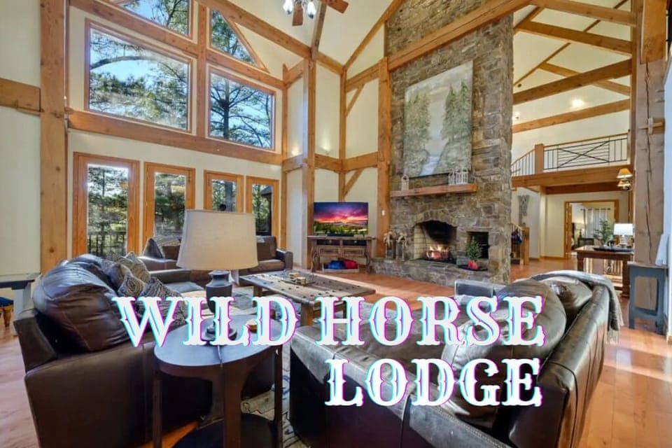 Living Room: Sunlit retreat with elegant stone fireplace and stunning forest views!