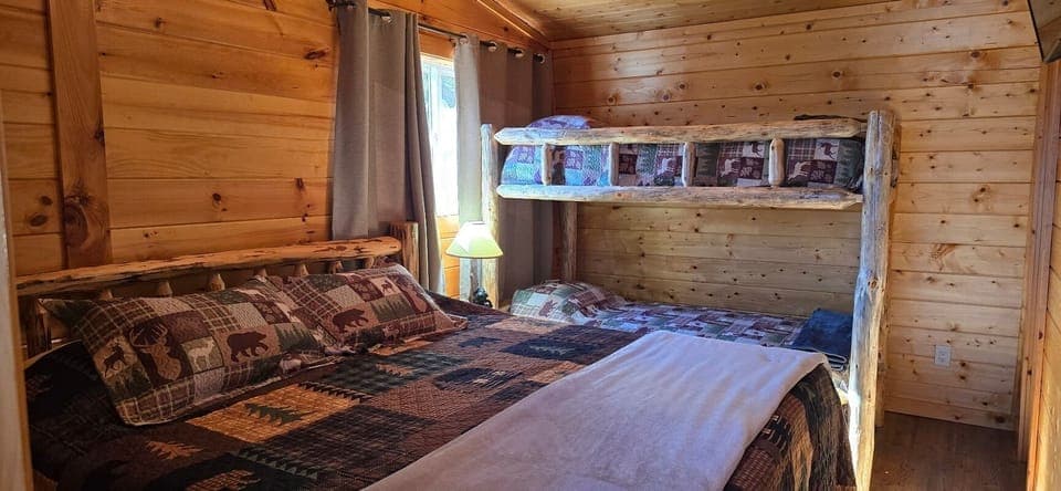 Cozy log cabin bedroom featuring rustic wood walls, warm, and a unique bunk bed arrangement perfect for families.